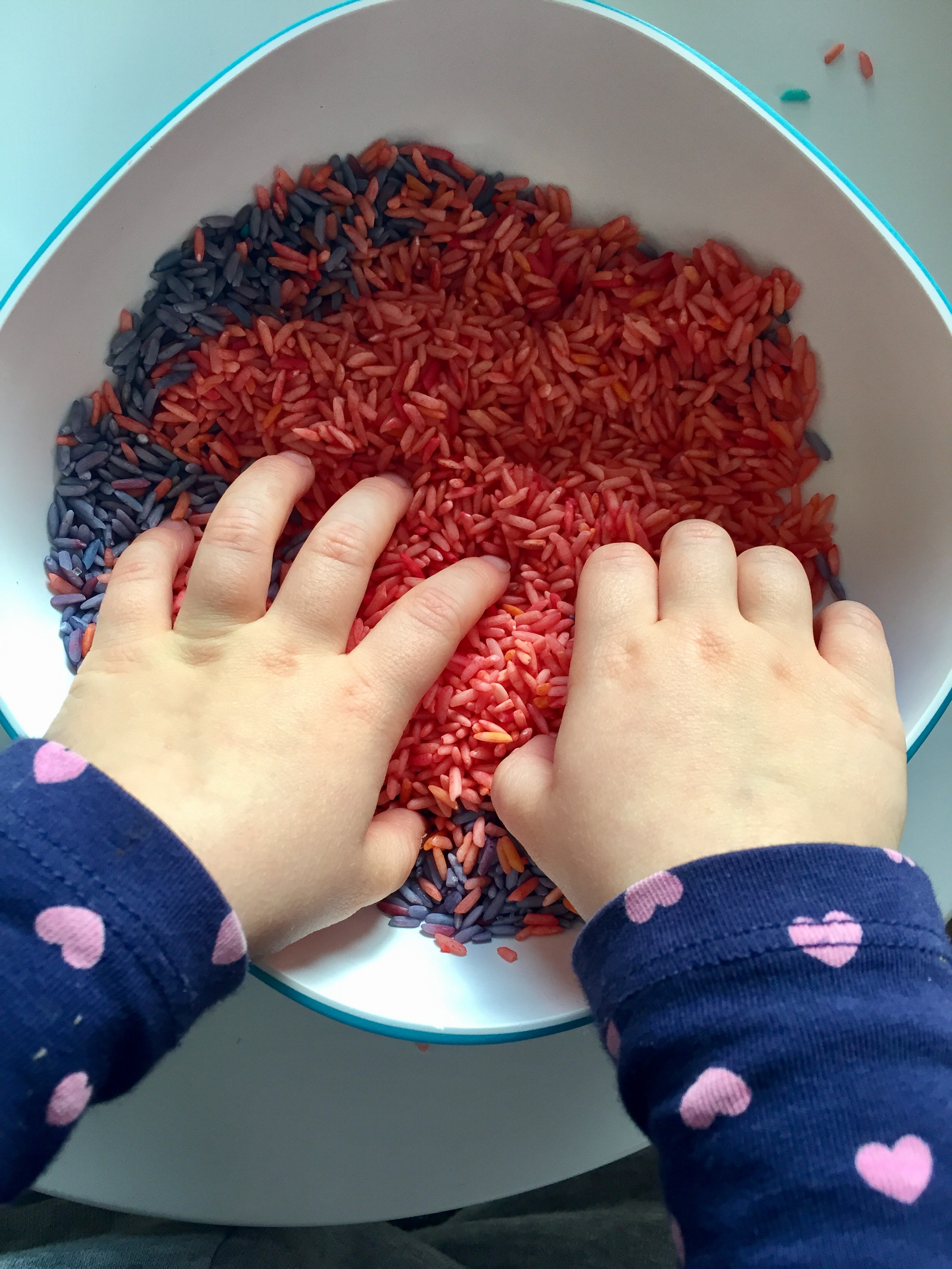 Bébé met ses mains dans du riz coloré