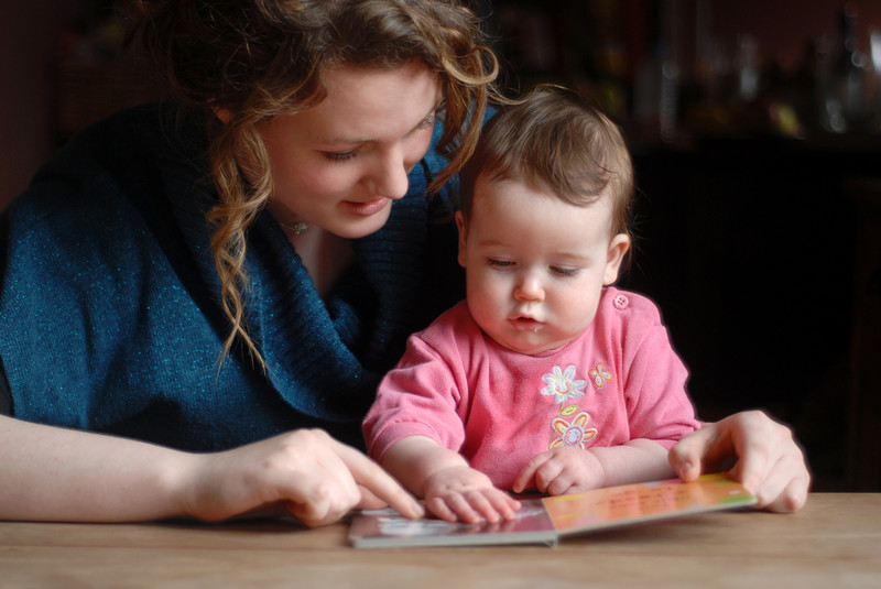 assistante maternelle regarde un livre avec un bébé