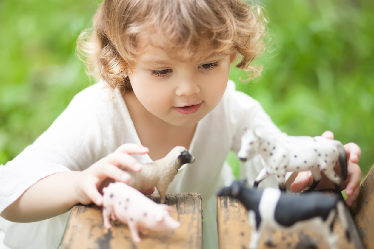 petite fille jouant avec figurines animaux de la ferme