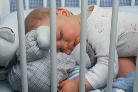 bébé dort dans lit à barreau