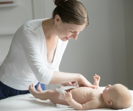 professionnelle de la petite enfance qui change la couche d'un bébé