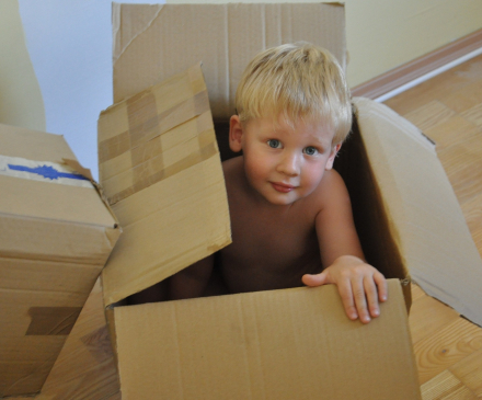 jeune enfant joue avec des cartons d'emballage
