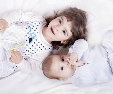 enfant et bébé sur un lit